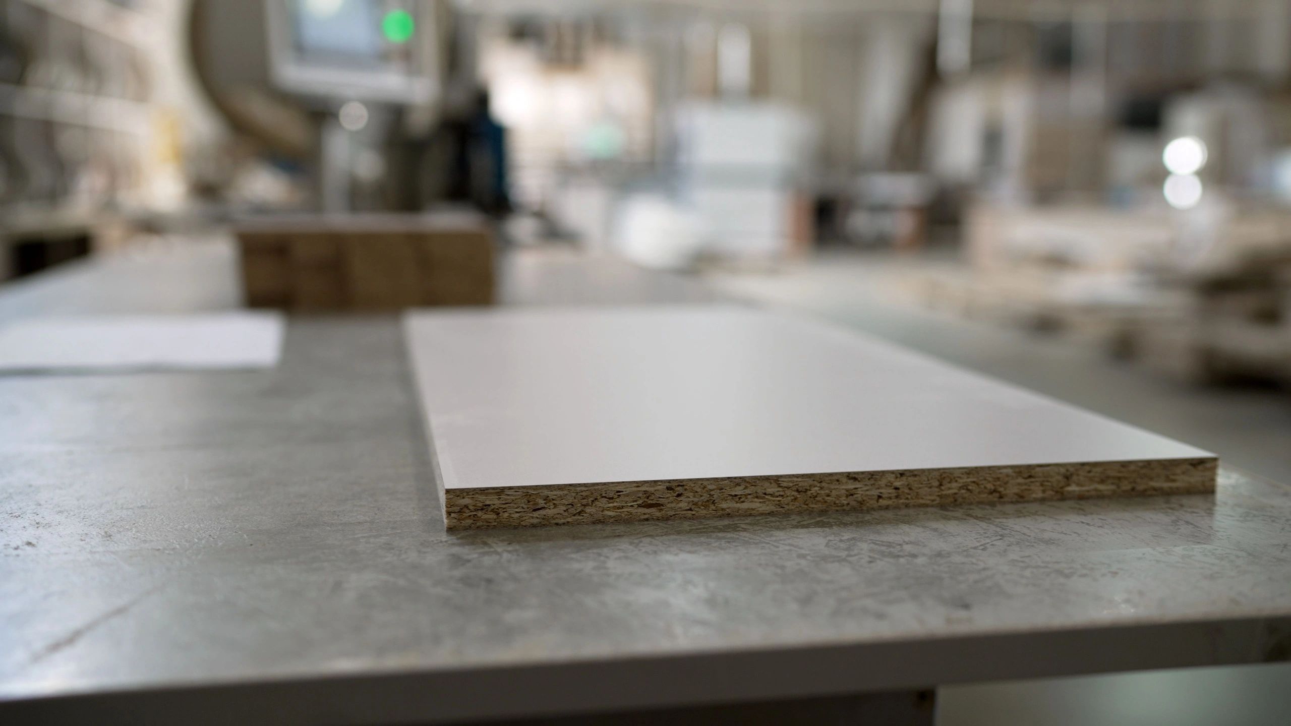 White laminated chipboard panel on a worktable in a furniture manufacturing workshop
